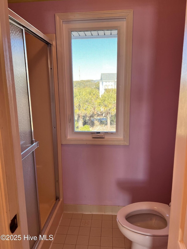 bathroom featuring a shower with shower door, tile patterned floors, and toilet