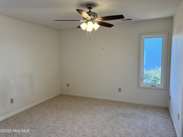 spare room with ceiling fan, light colored carpet, and a textured ceiling