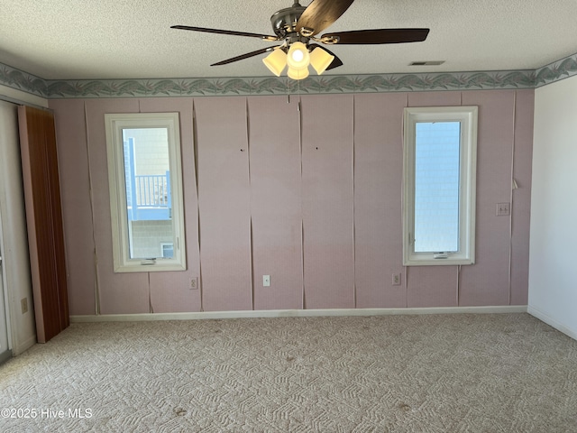 carpeted empty room featuring ceiling fan and a textured ceiling