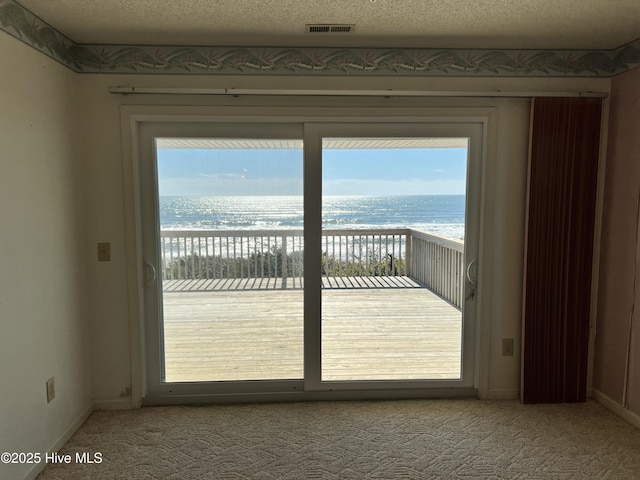 doorway featuring a water view, light carpet, and a textured ceiling