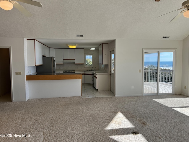 kitchen featuring white cabinetry, sink, stainless steel refrigerator, and kitchen peninsula