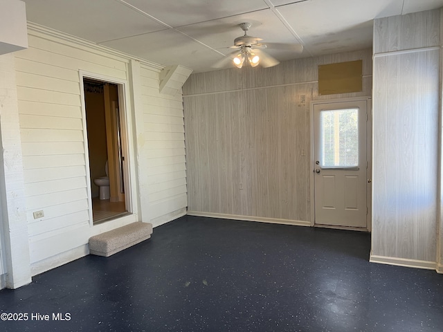 spare room featuring ceiling fan and wood walls