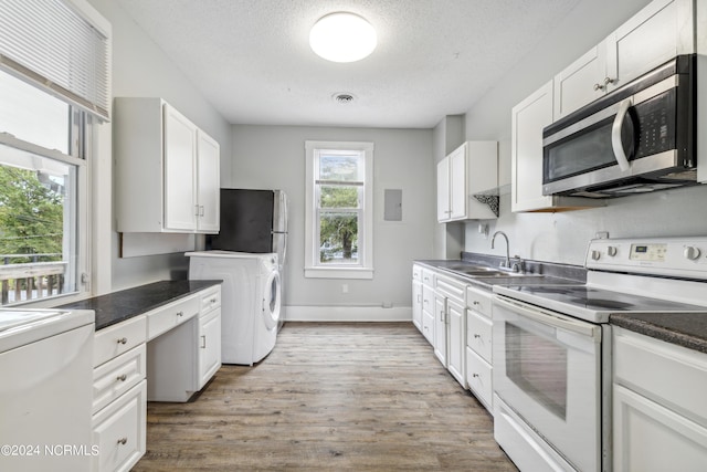 kitchen featuring a sink, white cabinetry, appliances with stainless steel finishes, light wood finished floors, and washer / dryer