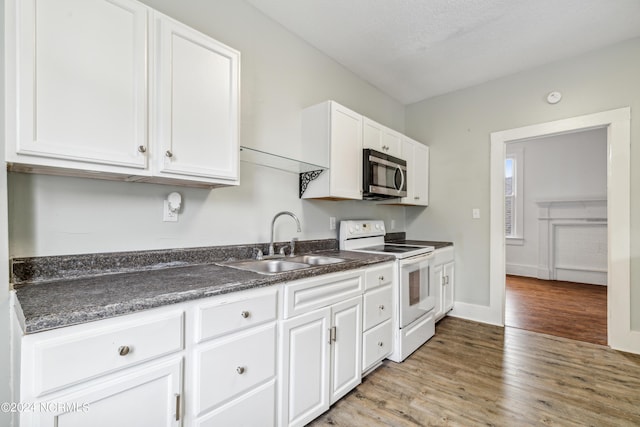 kitchen with white cabinets, stainless steel microwave, a sink, and white electric range oven