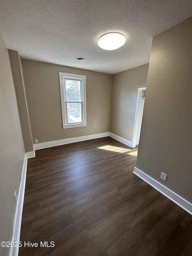 spare room with dark wood finished floors, a textured ceiling, and baseboards