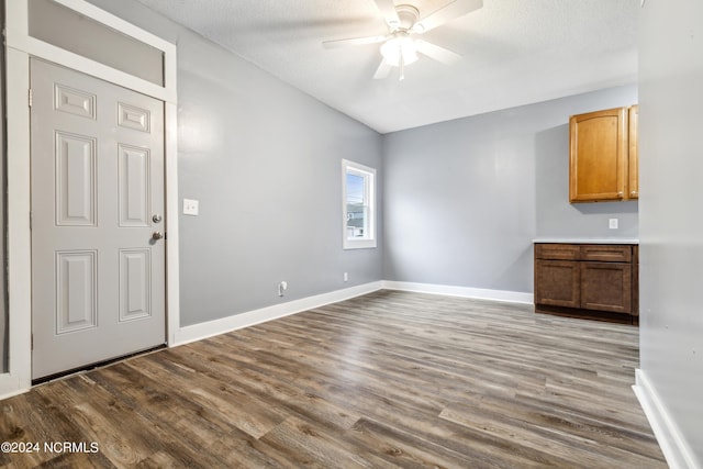 interior space with baseboards, a ceiling fan, and dark wood-style flooring