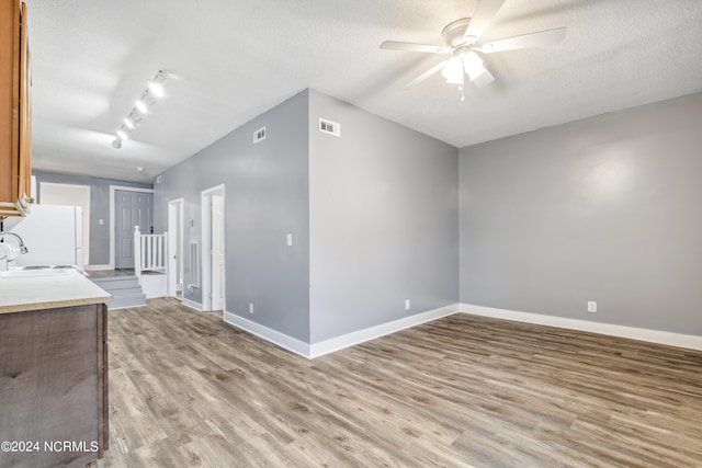 interior space featuring baseboards, visible vents, ceiling fan, a textured ceiling, and light wood-type flooring