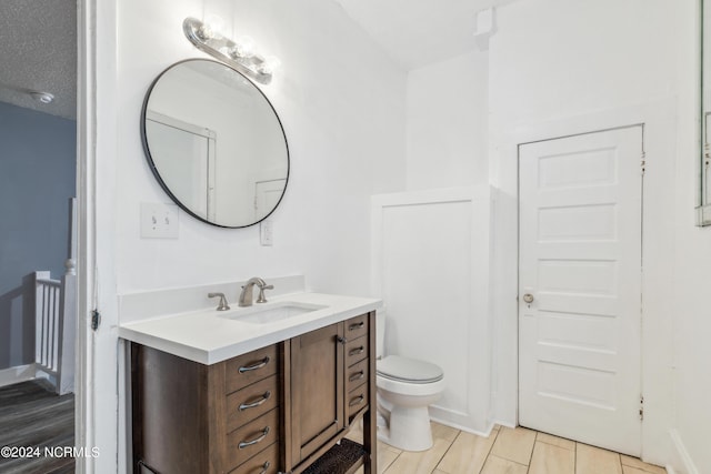 bathroom featuring toilet, a textured ceiling, and vanity