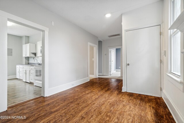 empty room with a sink, baseboards, visible vents, and wood finished floors