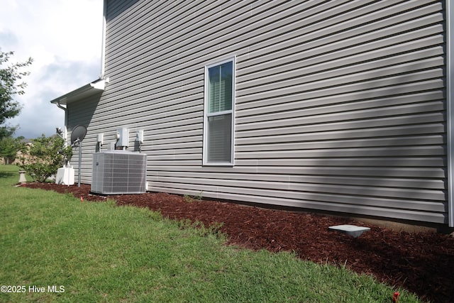 view of side of property with central AC and a lawn