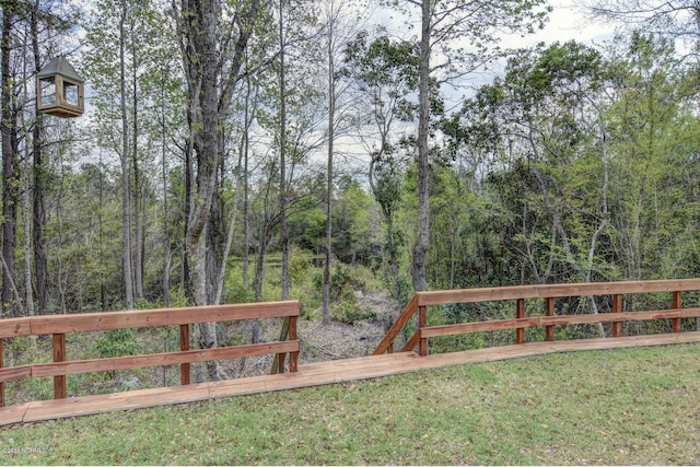 view of gate featuring a wooded view and a yard