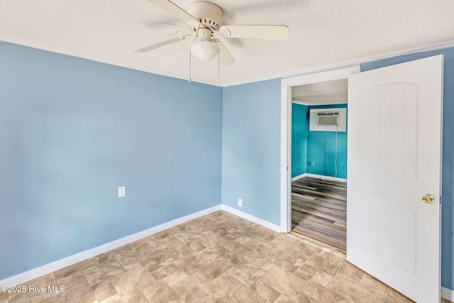 spare room with baseboards, a wall mounted AC, ceiling fan, and a textured ceiling