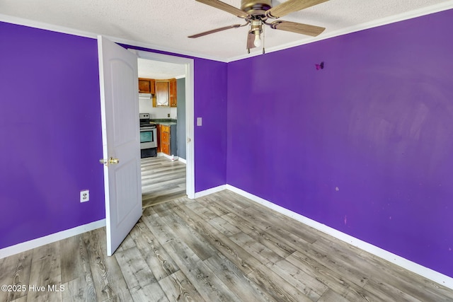 spare room with a ceiling fan, wood finished floors, baseboards, and a textured ceiling