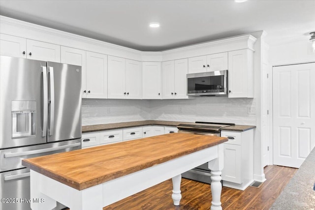 kitchen featuring tasteful backsplash, white cabinetry, appliances with stainless steel finishes, and wooden counters