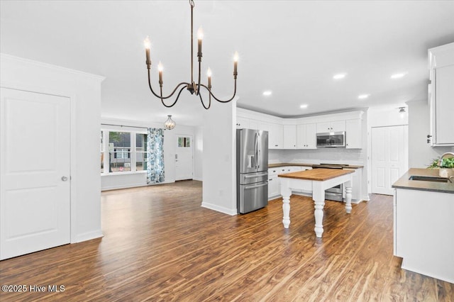 kitchen featuring hanging light fixtures, appliances with stainless steel finishes, dark wood-type flooring, and white cabinets