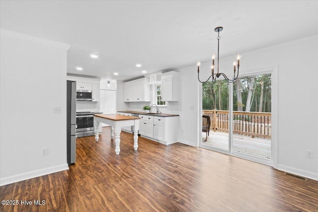 kitchen featuring stainless steel appliances, sink, butcher block countertops, and white cabinets