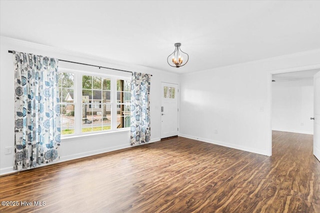 empty room featuring an inviting chandelier, ornamental molding, and dark hardwood / wood-style floors