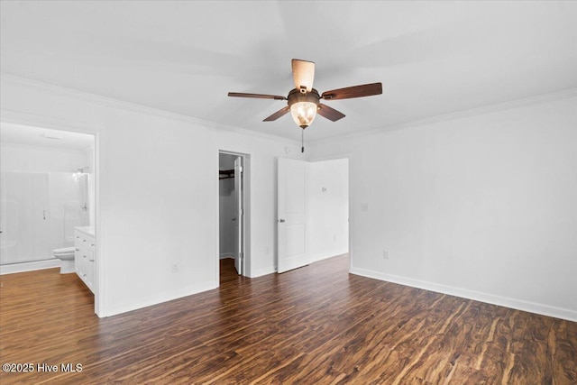 unfurnished bedroom featuring dark hardwood / wood-style flooring, crown molding, and a spacious closet