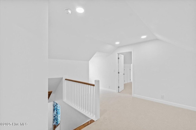 hallway with lofted ceiling and light carpet