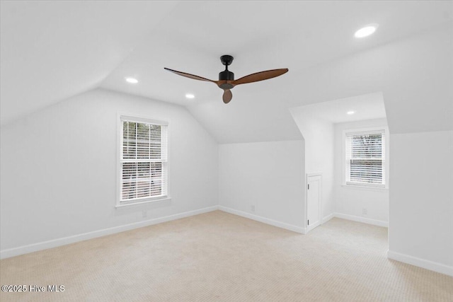 additional living space with light colored carpet, a healthy amount of sunlight, and lofted ceiling