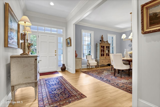 entryway with an inviting chandelier, light hardwood / wood-style flooring, and ornamental molding