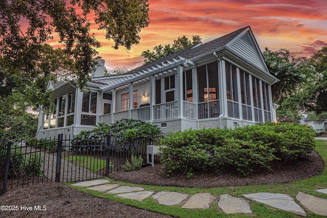 property exterior at dusk featuring a sunroom and a pergola