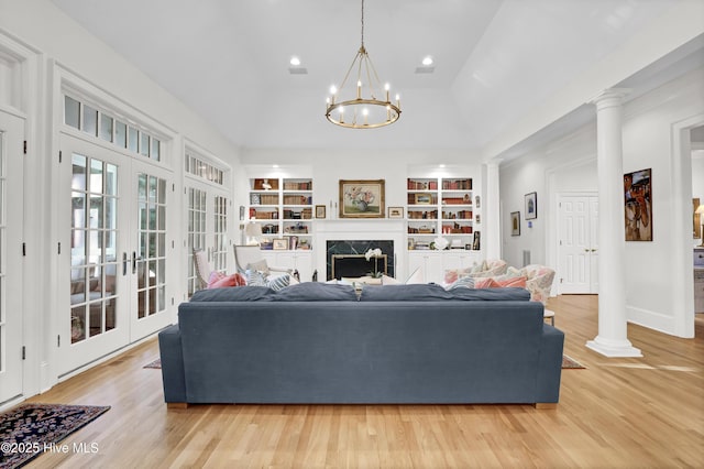 living room featuring a fireplace, light hardwood / wood-style floors, decorative columns, and built in features