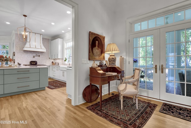 interior space with premium range hood, french doors, and white cabinets