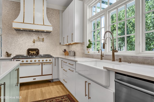 kitchen with dishwasher, white cabinetry, double oven range, backsplash, and range hood