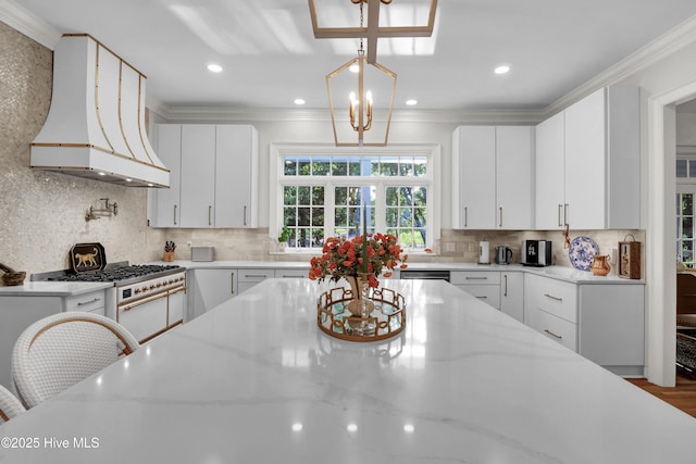 kitchen with custom range hood, pendant lighting, white cabinets, and light stone counters