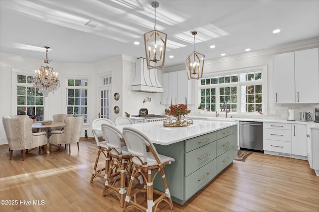 kitchen with appliances with stainless steel finishes, white cabinetry, a center island, custom exhaust hood, and a chandelier