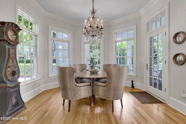 dining area with an inviting chandelier, crown molding, and light wood-type flooring