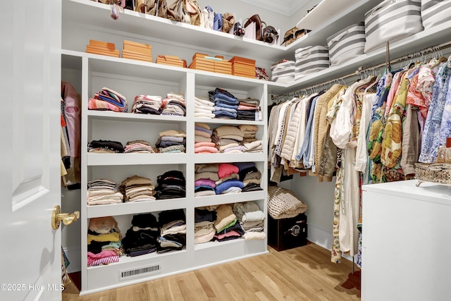 walk in closet with light hardwood / wood-style flooring