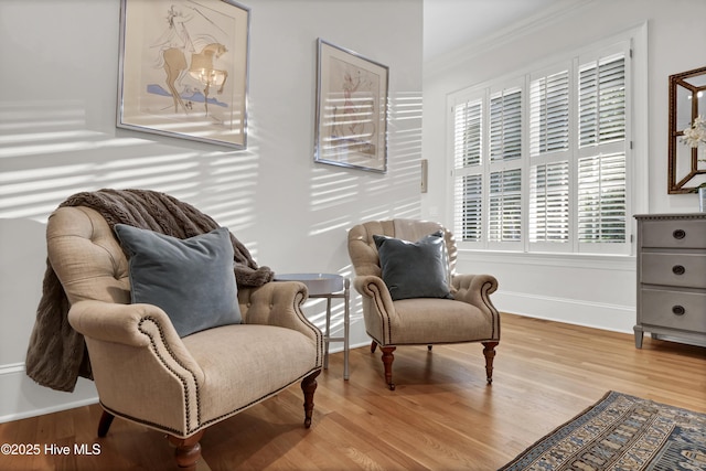 sitting room with ornamental molding and light hardwood / wood-style flooring