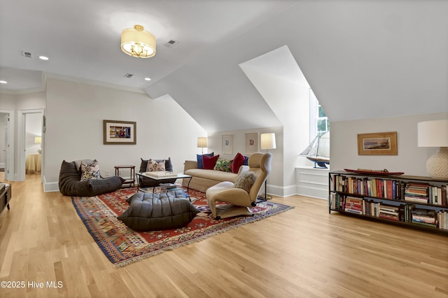 living room with ornamental molding, vaulted ceiling, and light wood-type flooring