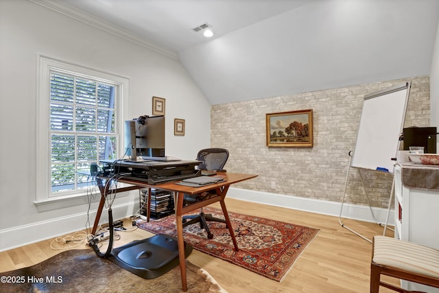 home office featuring brick wall, vaulted ceiling, and light wood-type flooring