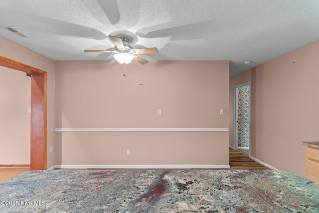 unfurnished bedroom with ceiling fan and a textured ceiling