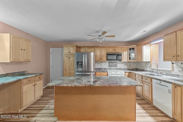 kitchen featuring light stone countertops, a center island, sink, and white appliances