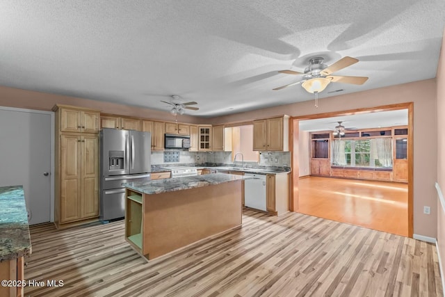 kitchen with sink, tasteful backsplash, a center island, white appliances, and light hardwood / wood-style floors