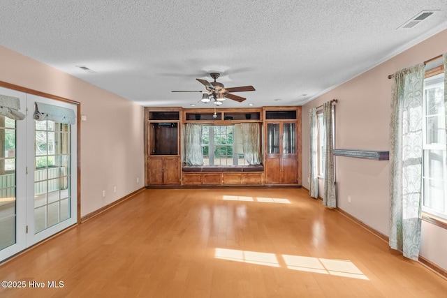 unfurnished living room with a healthy amount of sunlight, a textured ceiling, and light wood-type flooring