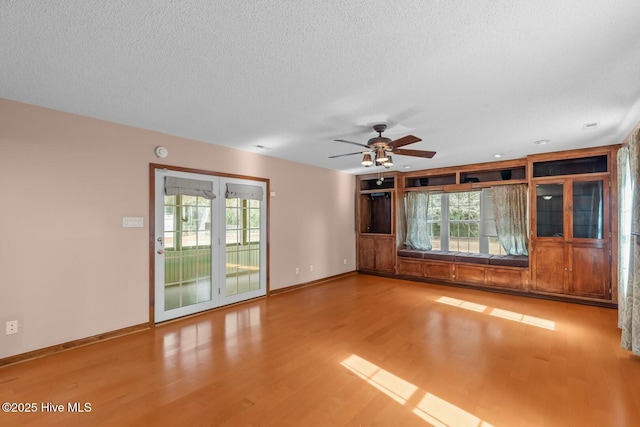 unfurnished living room featuring a wealth of natural light, hardwood / wood-style floors, ceiling fan, and a textured ceiling