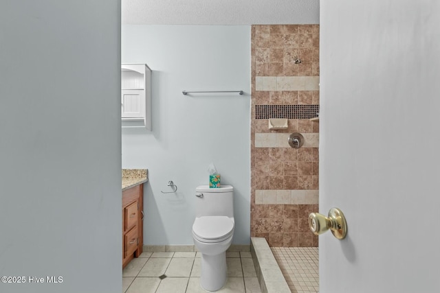 bathroom with vanity, a tile shower, a textured ceiling, tile patterned floors, and toilet