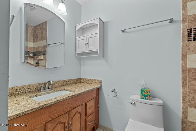 bathroom with tiled shower, vanity, and toilet