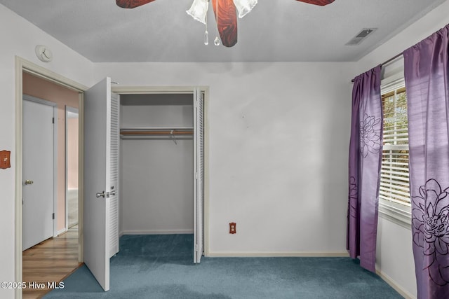 unfurnished bedroom featuring dark colored carpet, a textured ceiling, and a closet