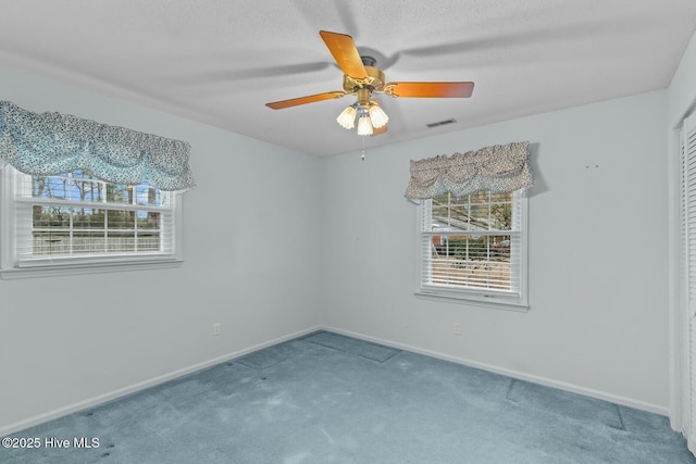 empty room with a textured ceiling, a wealth of natural light, ceiling fan, and carpet