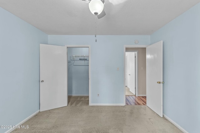 unfurnished bedroom featuring a walk in closet, light colored carpet, and a closet