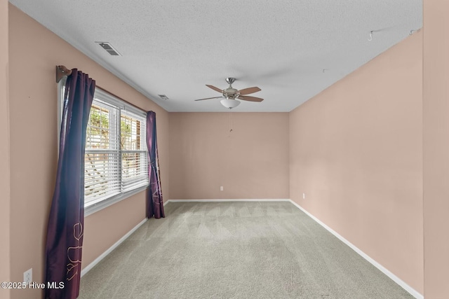 spare room with ceiling fan, light colored carpet, and a textured ceiling