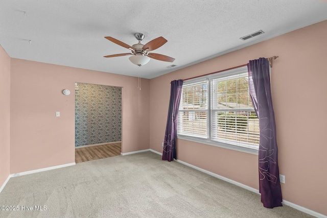 unfurnished room with ceiling fan, light colored carpet, and a textured ceiling