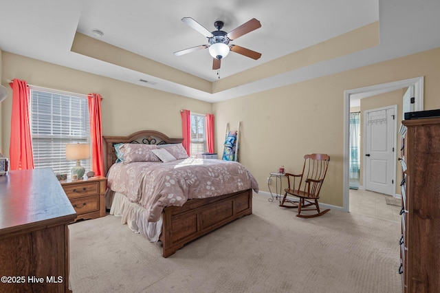 carpeted bedroom featuring a raised ceiling and ceiling fan