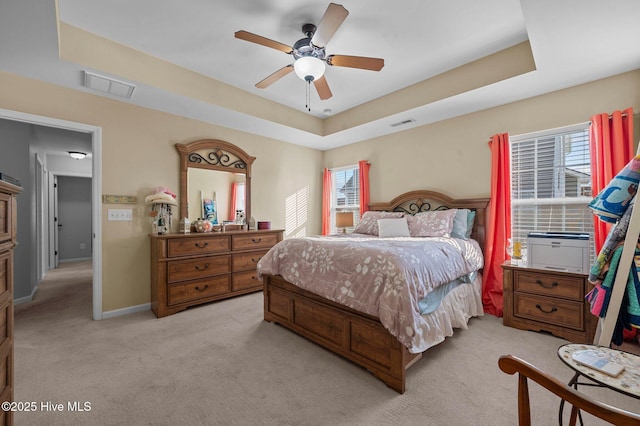 carpeted bedroom featuring ceiling fan and a tray ceiling